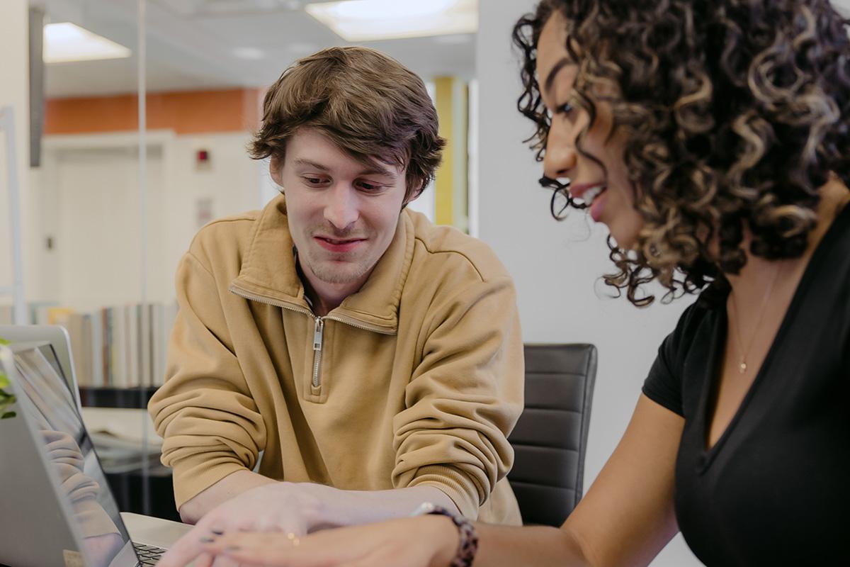 Two business administration students study together at a laptop